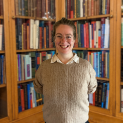 Photo of Helen Symington, standing in front of bookshelves