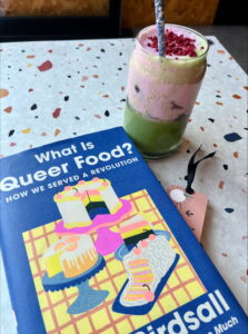 Photo of book cover 'What is Queer Food? How we served up a revolution' with a colourful pink and green matcha drink.