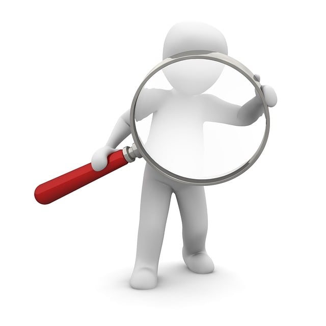 Human figure holding and looking through a magnifying glass
